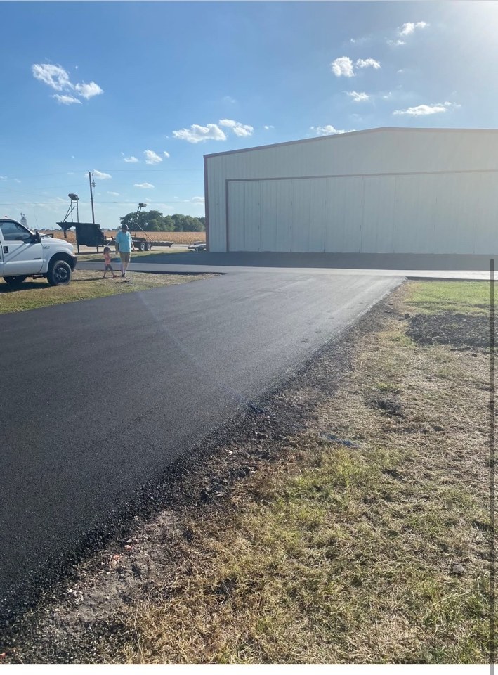 Completed asphalt drive leading to a large building